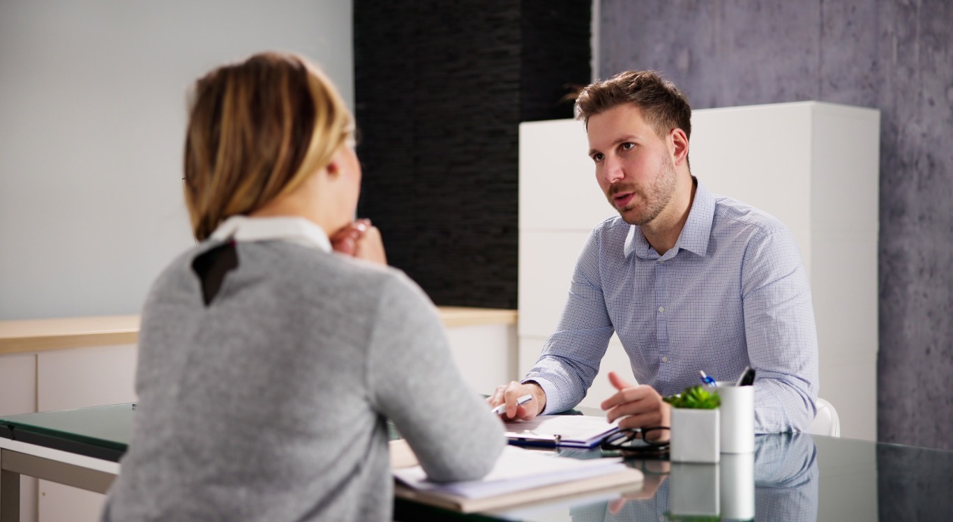 Ein Mann und eine Frau führen ein konzentriertes Gespräch an einem Schreibtisch.